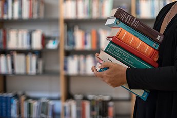 Kvinna håller boktrave i famnen. Foto: Björn Bjarnesjö.